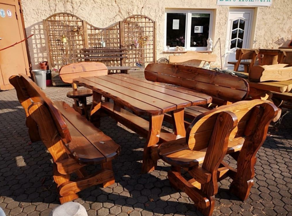 Rustikales Gartenmöbel-Set aus massivem Holz mit Tisch, Bänken und Stühlen auf gepflasterter Terrasse im Freien.